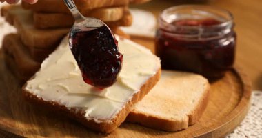 Masada yağlı tost üzerine reçel koyan kadın, yakın plan.