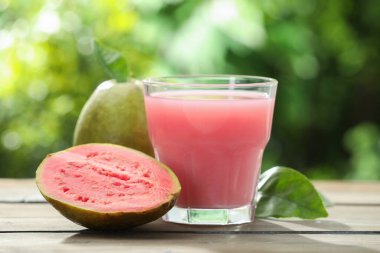 Guava suyunu tazeliyorum ve ahşap masada taze meyveler, yakın plan.