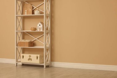 Shelving unit with decor near beige wall indoors, space for text