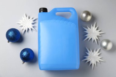Plastik şişede antifriz, takılar ve gri arka planda dekoratif kar taneleri.