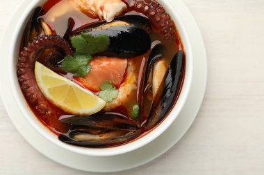 Hafif ahşap masada, tabakta nefis deniz ürünleri çorbası.