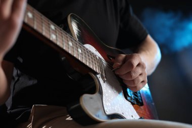 Karanlık arka planda gitar çalan adam dumanlı, yakın plan
