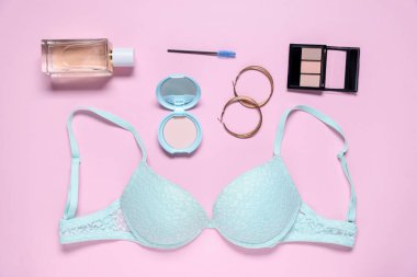 Pembe arka planda dantel sutyen ve kozmetik ürünlerle düz konum