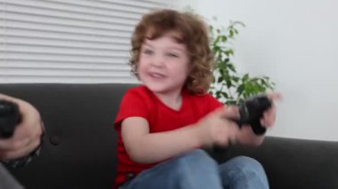 Mutlu oğul ve babası evde oyun kontrolörleriyle oynuyorlar.