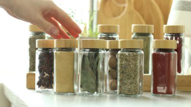 Baharat seçen bir kadın ve kapalı bir masada defne yapraklarıyla kavanoz alan bir kadın.