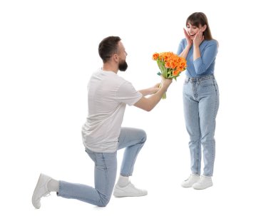 Adam beyaz arka planda sevgili karısına güzel laleler sunuyor.