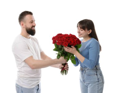 Adam beyaz arka planda sevgilisine kırmızı gül buketi sunuyor.