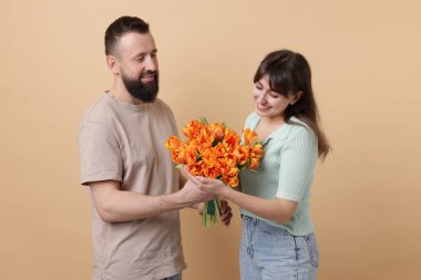 Adam bej arka planda sevgili karısına güzel laleler sunuyor.