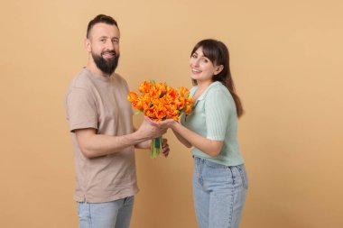 Adam bej arka planda sevgili karısına güzel laleler sunuyor.