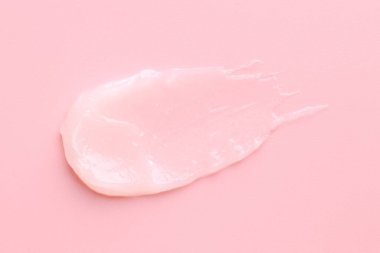 Pembe arka planda nemlendirici dudak kremi, üst manzara.