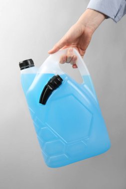 Açık gri arka planda antifriz kutusu olan kadın, yakın plan.