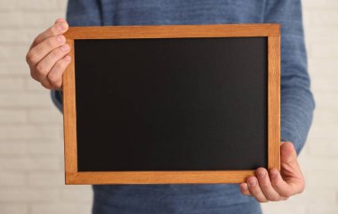 Kapalı alanda boş küçük tahta tutan adam, yakın plan.