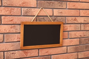 Tuğla duvarda boş küçük bir tahta.