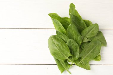 Beyaz ahşap masa üzerinde taze yeşil kuş yaprakları yığını, üst manzara. Metin için boşluk