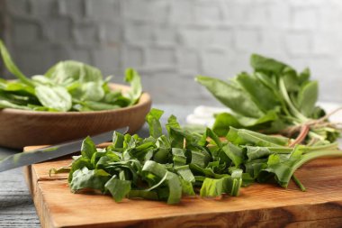 Gri ahşap masada taze kuş yaprakları ve bıçak kes, yakın plan.