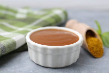 Lezzetli köri sosu, toz ve fesleğen yaprakları gri masada, yakın plan.