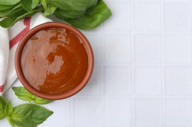 Lezzetli köri sosu ve fesleğen yaprakları beyaz fayanslı masada, düz yerde. Metin için boşluk