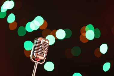 Karanlık arka planda bulanık ışıkları olan klasik mikrofon, mesaj için yer. Müzik ekipmanları