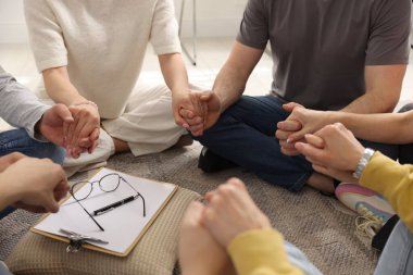 Grup psikoterapi seansı sırasında el ele tutuşan insanlar kapalı mekanda, yakın çekim