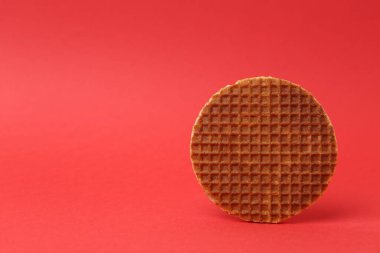 Kırmızı arka planda lezzetli yuvarlak bir waffle. Metin için boşluk