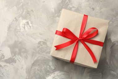 Kraft kağıdına sarılı bir hediye, gri desenli arka plan, üst manzara. Metin için boşluk