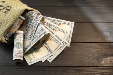 Gri ahşap masanın üzerinde dolar banknotları olan para çantası, yakın plan. Metin için boşluk