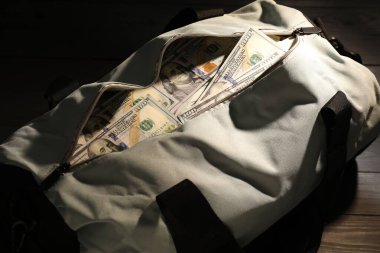 Tahta masanın üzerinde dolar banknotları olan çanta, yakın plan.