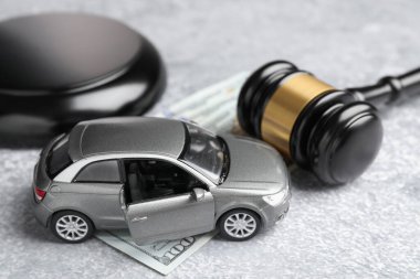 Motorlu taşıt kazası yasası. Gavel, para ve araba modeli gri arka planda, yakın plan.