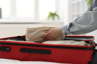 Giysileri paketleme kübüne koyan kadın, yakın plan.