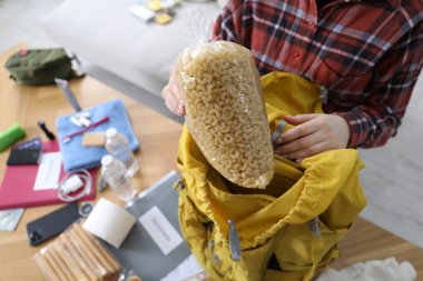 Hayatta kalma kiti. İçerideki masada sırt çantasına çiğ makarna koyan bir kadın.