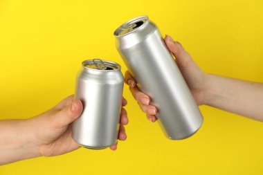 Sarı arka planda teneke kutuları olan kadınlar, yakın plan