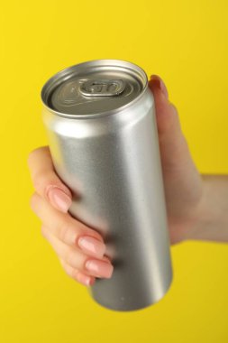 Sarı arka planda teneke kutusu olan kadın, yakın plan.