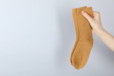 Açık gri arka planda bir çift çorap giyen kadın, yakın plan. Metin için boşluk