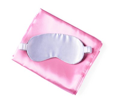 Beyaz arka planda ipek çarşaflar ve uyku maskesi, üst manzara.