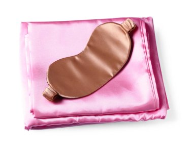 Beyaz arka planda ipek çarşaflar ve uyku maskesi, üst manzara.