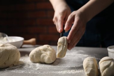 Açık gri masada hamur kesen kadın, yakın plan.