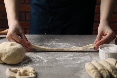 Açık gri masada simit yapan kadın, yakın plan.