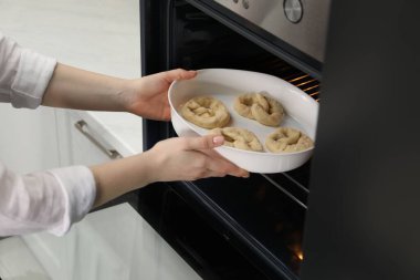 Pişmemiş krakerlerle fırına yemek koyan kadın, yakın plan.