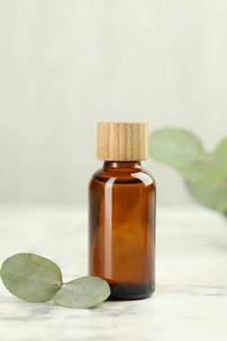 Gerekli yağ ve okaliptüs yaprakları beyaz mermer masanın üzerinde, yakın plan.