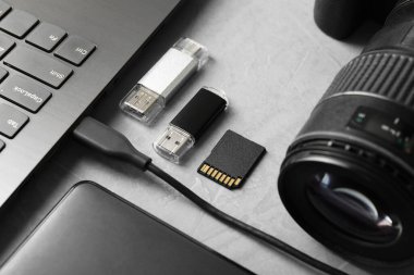 Flaş bellek, SD hafıza kartı, harici hard disk, dizüstü bilgisayar ve kamera gri desenli tabloda, yakın plan