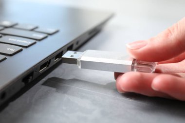 Gri desenli masadaki dizüstü bilgisayara bir kadın yerleştiriyor. Yakın plan.