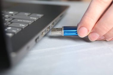 Gri masadaki flash belleğe bir kadın yerleştiriyor.