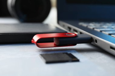 Dizüstü bilgisayara, SD hafıza kartına ve gri masadaki harici sabit diske bağlı flaş bellek.