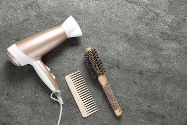 Gri dokulu arka planda farklı saç şekillendirme araçları, düz yatış. Metin için boşluk