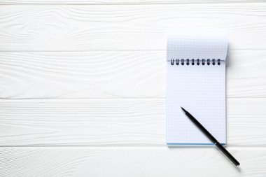 Kalem ve açık defter beyaz ahşap masa, üst manzara. Metin için boşluk