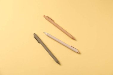 Sarı arka planda şık kalemler, düz yatış