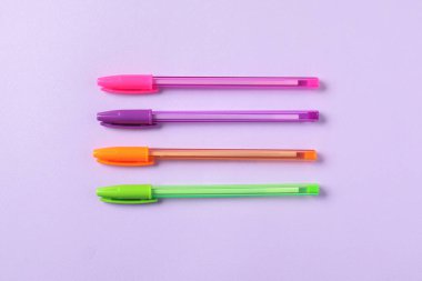 Menekşe arkaplan üzerinde şık kalemler, düz yatış