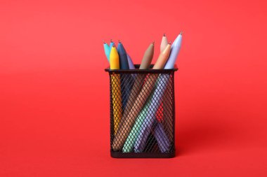 Kırmızı arkaplanda duran tükenmez kalemler, yakın plan