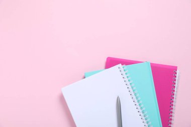 Kalem ve defterler pembe arka planda, en üstte. Metin için boşluk