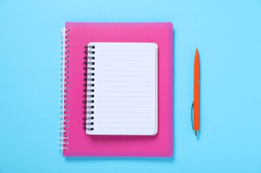 Açık mavi arkaplan üzerine dizüstü kalem ve defterler, düz konum